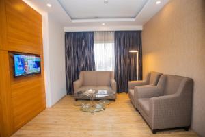 um quarto com duas cadeiras e uma mesa e uma televisão em Days Hotel Dhaka em Daca