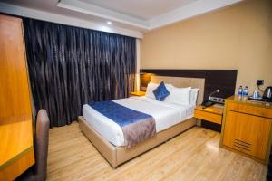 a hotel room with a bed and a desk and a window at Days Hotel Dhaka in Dhaka