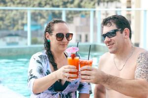 a man and a woman holding drinks next to a pool at Estação Termas Hotel in Piratuba