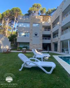 a building with two lounge chairs and a swimming pool at Alley Pampa in Mar de las Pampas