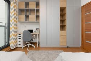 Spacious Apartment Premium Warszawa Wola by Renters Prestige في وارسو: غرفة نوم مع مكتب وكرسي في غرفة