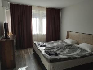 1 dormitorio con 1 cama y una ventana con cortinas en Апартамент Рая 2, en Dobrich