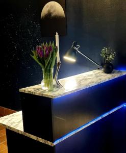 a counter with a vase of flowers and a lamp at Hotell Tre Systrar in Eskilstuna