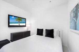 1 dormitorio con 1 cama blanca y TV en la pared en Oceanfront Private Residence at W South Beach -828, en Miami Beach