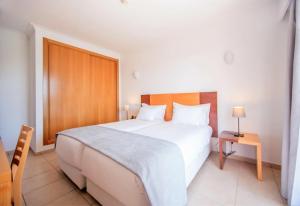 a bedroom with a large white bed and a table at Aquamar Albufeira Aparthotel in Albufeira