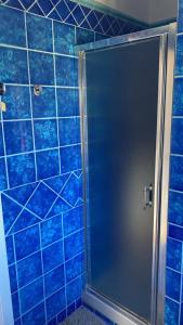 a blue tiled shower with a door in a bathroom at La casa di Nettuno in Naples