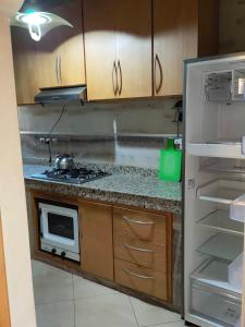 a kitchen with a stove and an open refrigerator at Appartement wifaq in Temara