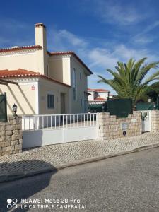 a white fence in front of a house at Villa Lala in Amoreira