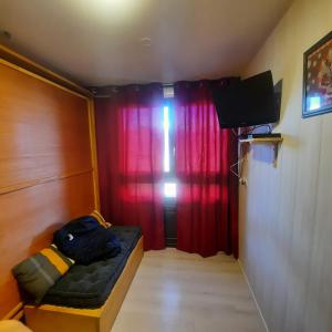 a small room with a couch and a red curtain at Studio pied des pistes saint lary in Saint-Lary-Soulan