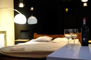 two wine glasses on a table next to a bed at City Apartment Getta in Krakow