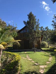 a house with a tree in front of a yard at Weekend Yoga Resort Paraíso dos Pândavas in Alto Paraíso de Goiás