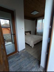 1 dormitorio con cama, ventana y puerta en At Chorbadzhiykata, en Kalofer