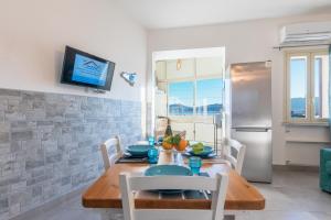 a kitchen with a wooden table with chairs and a refrigerator at Casa de Paoli - Vista Mare Arenella, Palermo con Parcheggio Privato in Palermo
