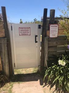 una puerta de metal con dos letreros al lado de una valla en Apartamentos La Playa, en Piriápolis