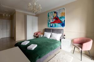 ein Schlafzimmer mit einem grünen Bett und einem Gemälde an der Wand in der Unterkunft Sun apartments in Kiew