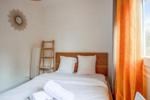 una camera da letto con letto, lenzuola e cuscini bianchi di Cosy apartment in Bagnolet close to Paris - Welkeys a Bagnolet