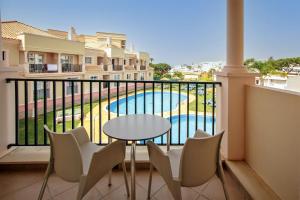 a balcony with a table and chairs and a pool at Aquamar Albufeira Aparthotel in Albufeira