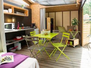 uma cozinha com uma mesa amarela e cadeiras num deque em Camping Emeraude em Saint-Briac-sur-Mer
