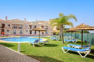 a group of chairs and umbrellas next to a swimming pool at Aquamar Albufeira Aparthotel in Albufeira