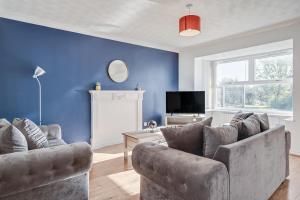 uma sala de estar com dois sofás e uma televisão em Spacious and Comfortable Home near Fosse Park em Kirby Muxloe