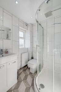 a white bathroom with a toilet and a shower at Spacious and Comfortable Home near Fosse Park in Kirby Muxloe