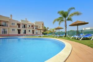 a large swimming pool with chairs and umbrellas at Aquamar Albufeira Aparthotel in Albufeira