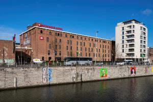 un edificio junto a un río con graffiti. en MEININGER Hotels Bruxelles City Center en Bruselas