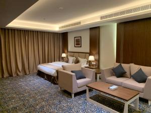 a hotel room with a bed and a couch and chairs at Al Diyafa Serviced Apartments in Al Ahsa