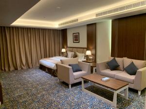 um quarto de hotel com uma cama e cadeiras e uma mesa em فندق ضيافة القرية Al Diyafa Hotel em Al Ahsa