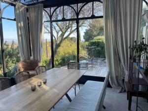 a table and chairs in a room with a large window at Maison Villa Provence Villeneuve les Avignon piscine vue Mont Ventoux in Villeneuve-lès-Avignon