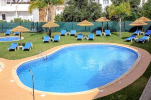 a large swimming pool with chairs and umbrellas at Aquamar Albufeira Aparthotel in Albufeira