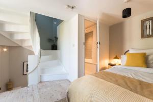 a white bedroom with a bed and a staircase at Talliers Cottage - Characterful & Central in Cirencester