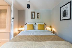 a bedroom with a large bed with yellow pillows at Talliers Cottage - Characterful & Central in Cirencester