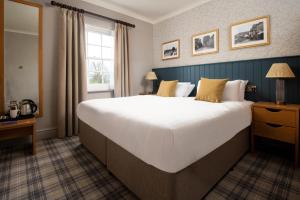 a large white bed in a room with a window at The Angel Inn - The Inn Collection Group in Bowness-on-Windermere