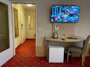 ein Büro mit einem Schreibtisch und einem TV an der Wand in der Unterkunft Hafner Hotel- Apartment in Stuttgart