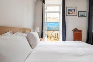 - une chambre avec un lit blanc et une vue sur l'océan dans l'établissement Le Hublot - Meublé Tourisme Classé 3 étoiles, à Cherbourg en Cotentin