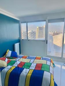 Un dormitorio con una cama colorida y una ventana en 14eme et dernier étage - 3 pieces "Arty" de 65 m2 avec vue panoramique !, en Créteil