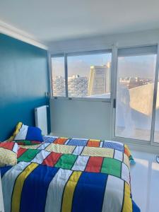 a bedroom with a colorful bed and a window at 14eme et dernier étage - 3 pieces "Arty" de 65 m2 avec vue panoramique ! in Créteil