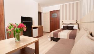 Una habitación de hotel con una cama y un jarrón de flores. en RizaVilla, en Krynica Morska