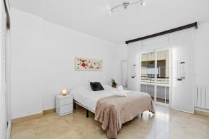 a white bedroom with a bed and a window at Casa Sierra Nevada in Granada