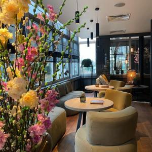 a lobby with tables and chairs and flowers at Cosmopolite Hotel Nieuwpoort-Bad in Nieuwpoort