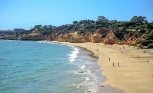 a beach with people on the sand and the ocean at Aquamar Albufeira Aparthotel in Albufeira