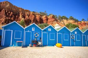 a blue building on the beach in front of a mountain at Aquamar Albufeira Aparthotel in Albufeira
