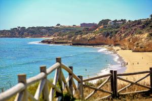 a view of a beach with a wooden fence at Aquamar Albufeira Aparthotel in Albufeira
