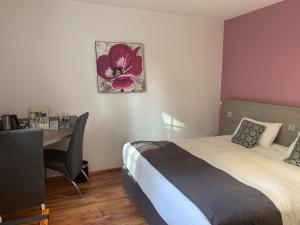 a bedroom with a bed and a desk with a computer at Logis Hôtel Le Moulin de la Coudre in Venoy