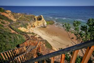a staircase leading down to a beach with the ocean at Aquamar Albufeira Aparthotel in Albufeira
