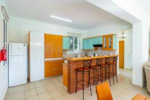 a kitchen with a bar with stools and a refrigerator at Villa Poseidon Gardens by Ezoria Villas in Larnaka