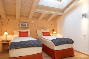 2 Betten in einem Zimmer mit Holzwänden in der Unterkunft Matterhorn Lodge Boutique Hotel & Apartments in Zermatt