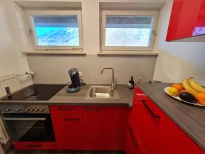 a red kitchen with a sink and a plate of fruit at Ferienwohnung Schlafende Hexe in Bad Reichenhall