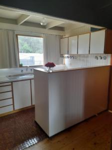 a kitchen with white cabinets and a large window at Beachouse in Lock Sport